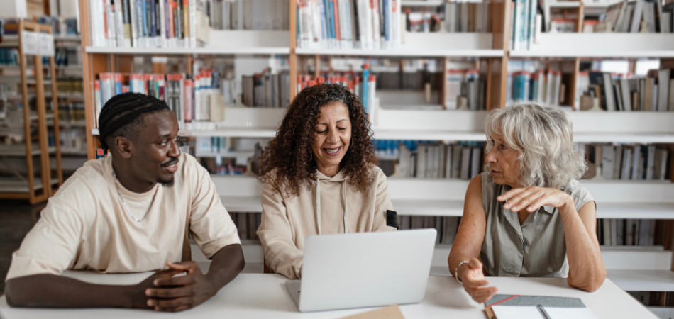 Three people meeting up in a library