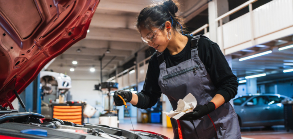A mechanic checking on the oil of a red car